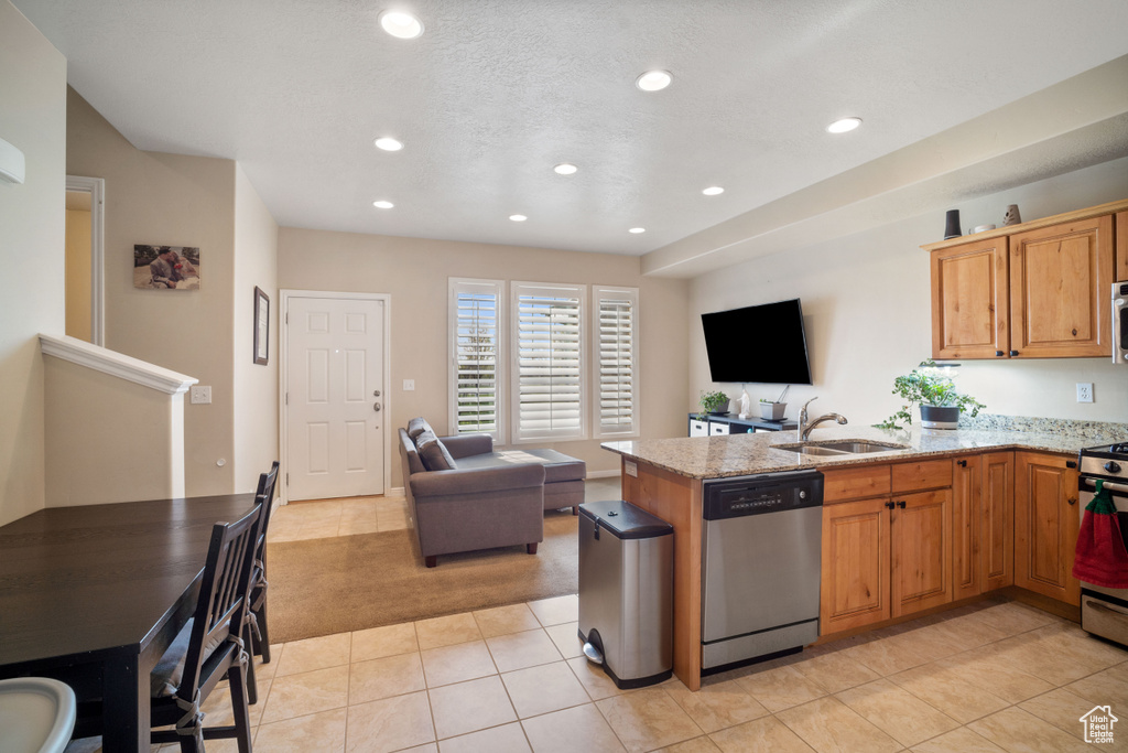 Kitchen with sink, stainless steel appliances, light tile floors, and light stone counters