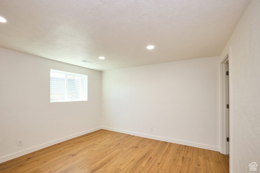 Unfurnished room featuring light hardwood / wood-style floors and a textured ceiling