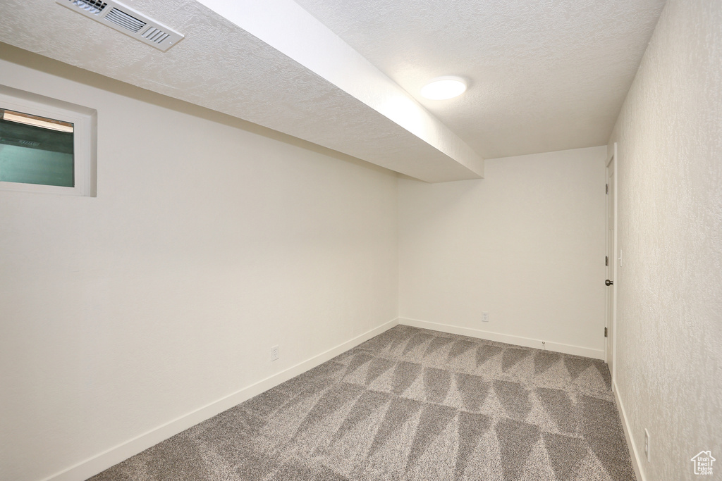 Spare room featuring a textured ceiling and carpet flooring
