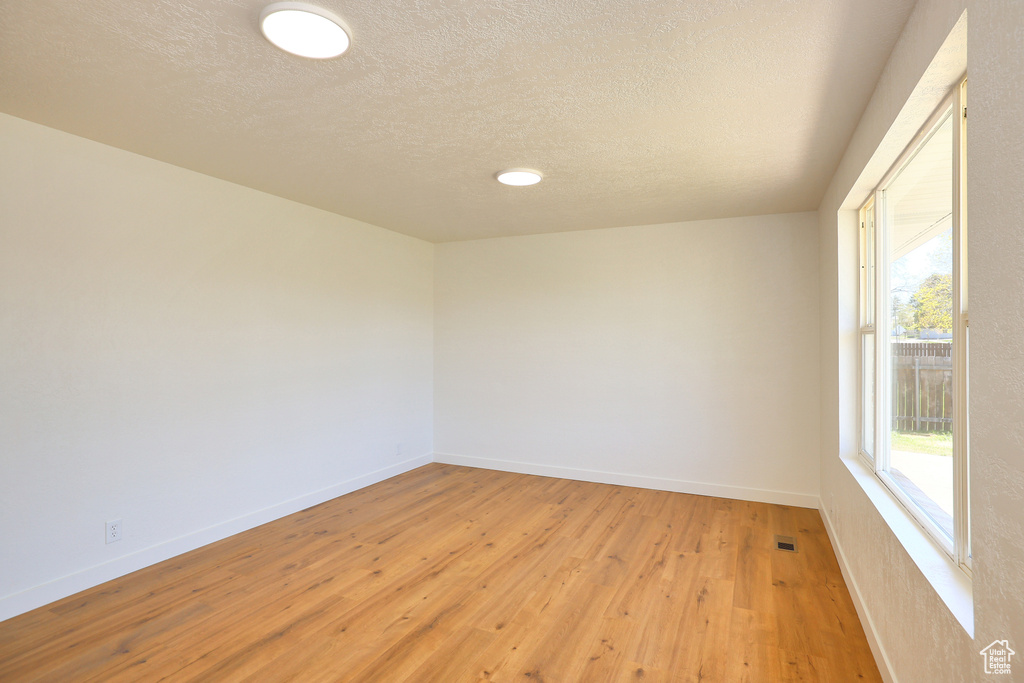 Spare room featuring light hardwood / wood-style floors and a textured ceiling