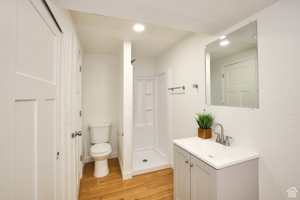 Bathroom featuring walk in shower, vanity, toilet, and hardwood / wood-style flooring