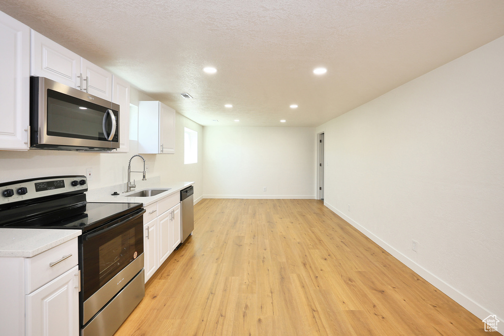 Kitchen featuring light hardwood / wood-style floors, stainless steel appliances, white cabinetry, and sink