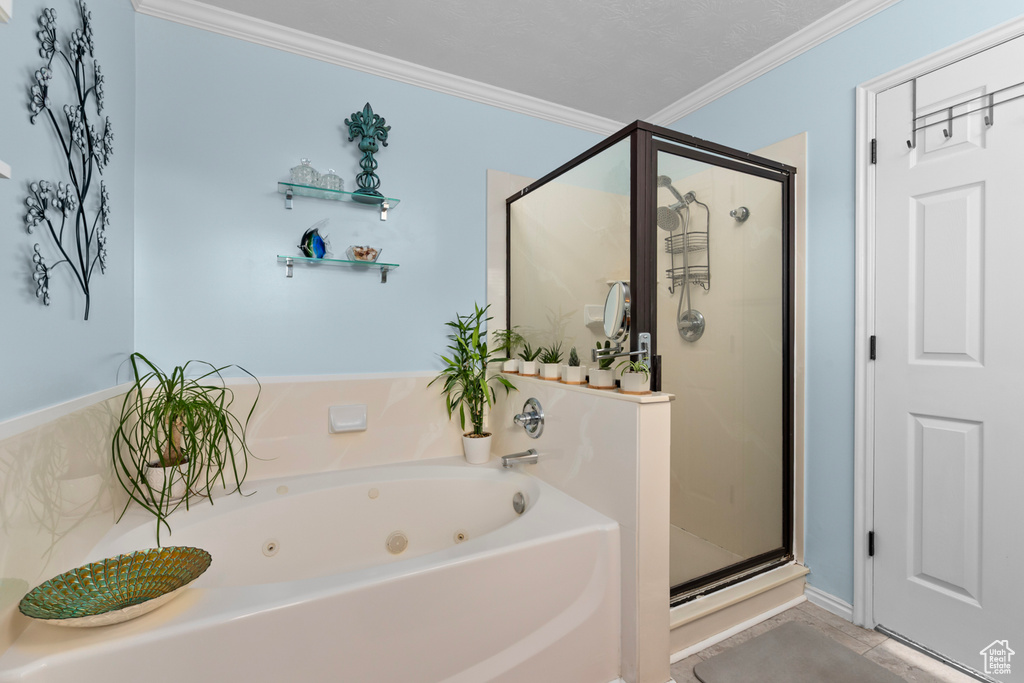 Bathroom featuring tile flooring, crown molding, shower with separate bathtub, and a textured ceiling