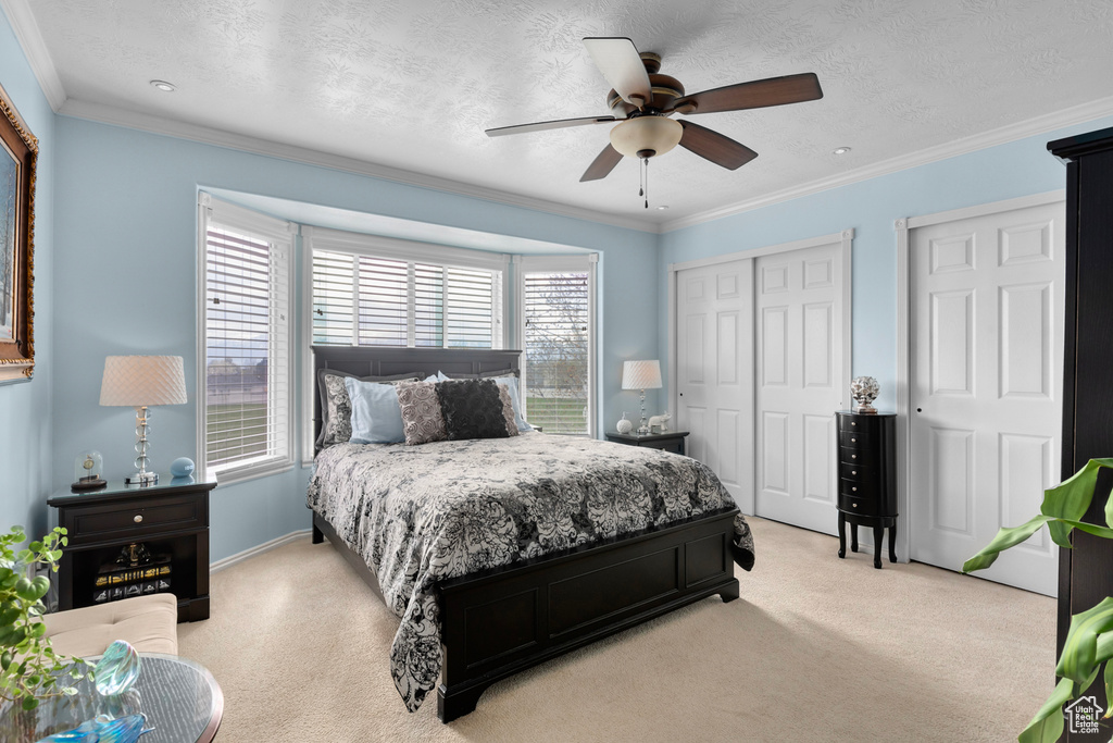 Carpeted bedroom featuring ornamental molding, ceiling fan, and a textured ceiling