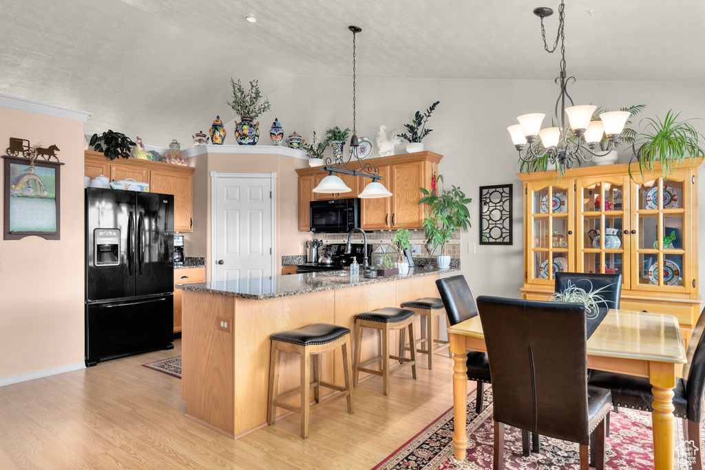 Kitchen with decorative light fixtures, a notable chandelier, light hardwood / wood-style flooring, and black appliances