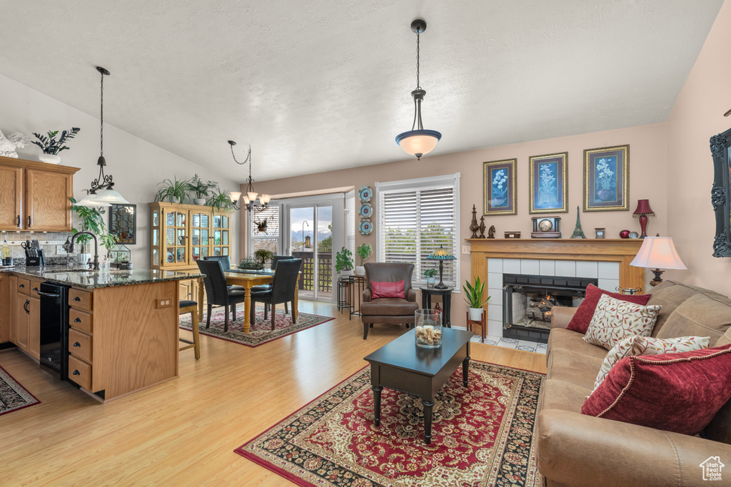 Living room featuring a tiled fireplace, light hardwood / wood-style floors, and vaulted ceiling