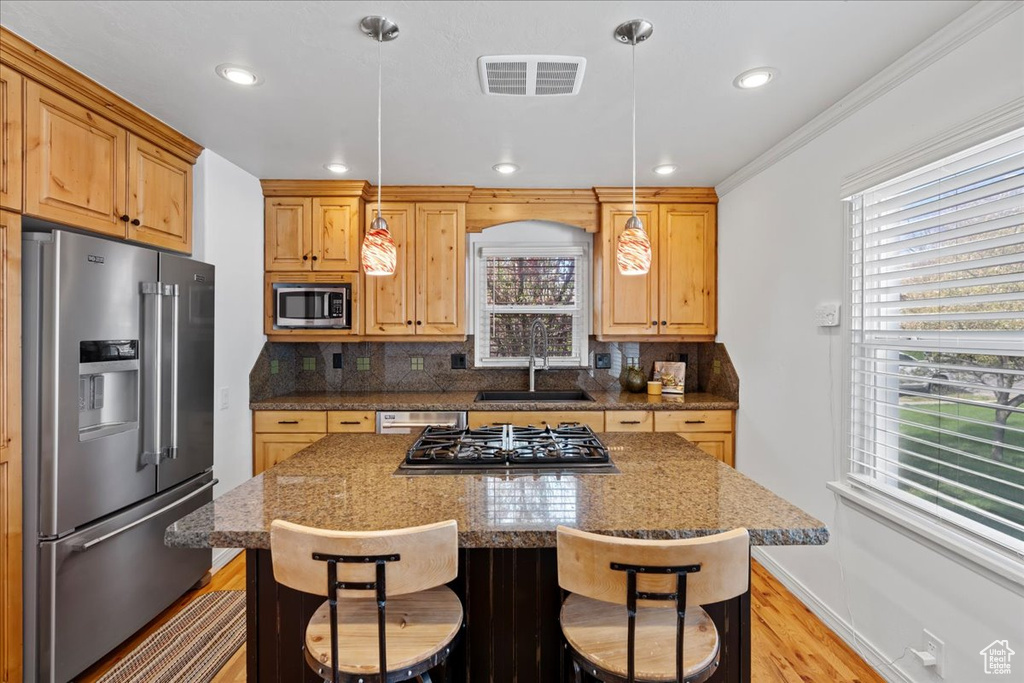 Kitchen with decorative light fixtures, appliances with stainless steel finishes, tasteful backsplash, and dark stone counters