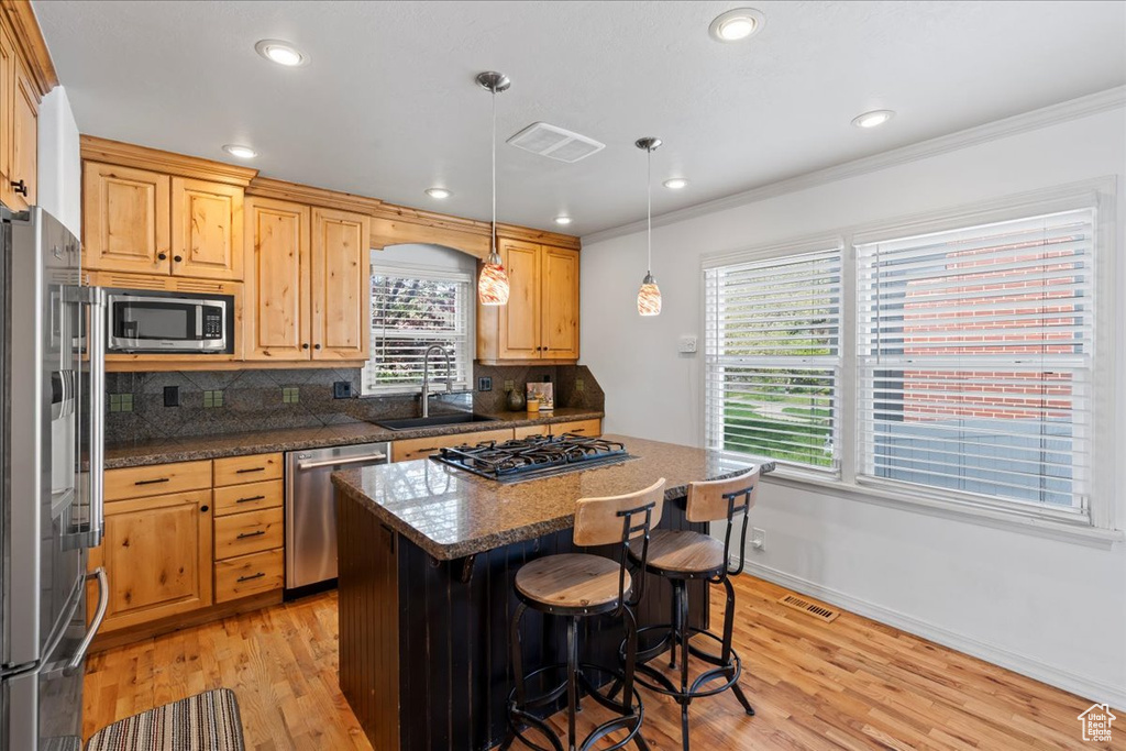 Kitchen featuring appliances with stainless steel finishes, light hardwood / wood-style floors, and backsplash