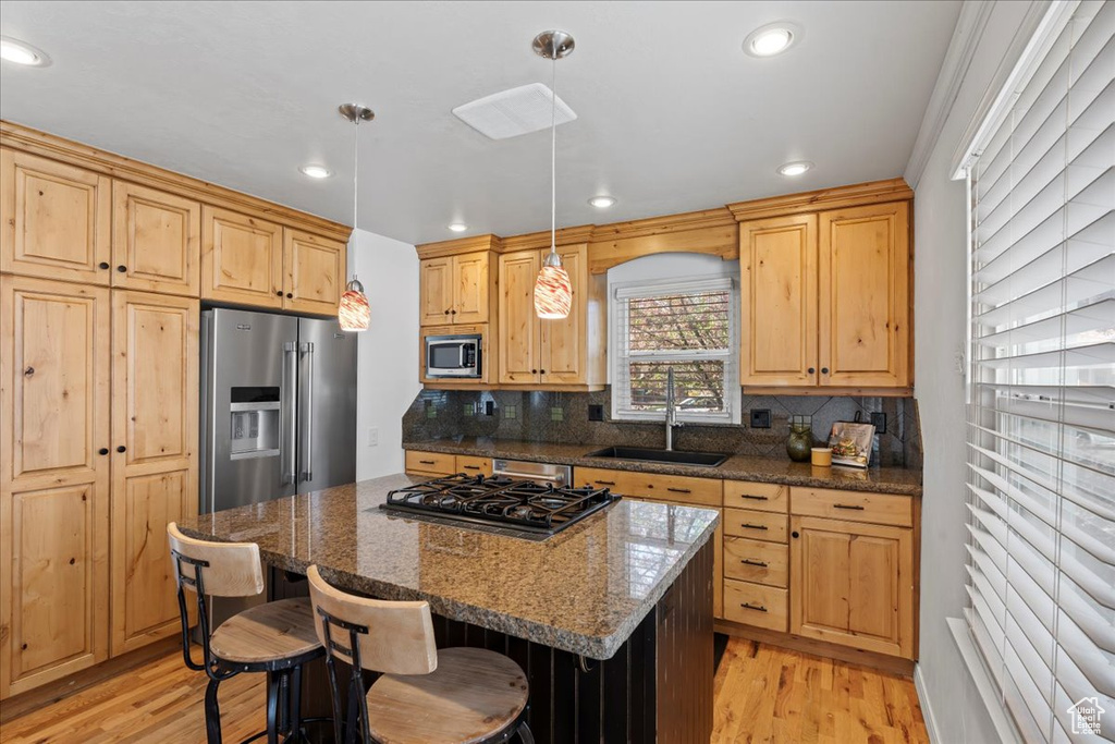 Kitchen featuring a kitchen breakfast bar, pendant lighting, stainless steel appliances, sink, and a kitchen island