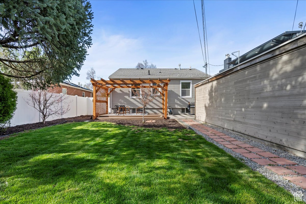 Back of property featuring a lawn, a patio, and a pergola