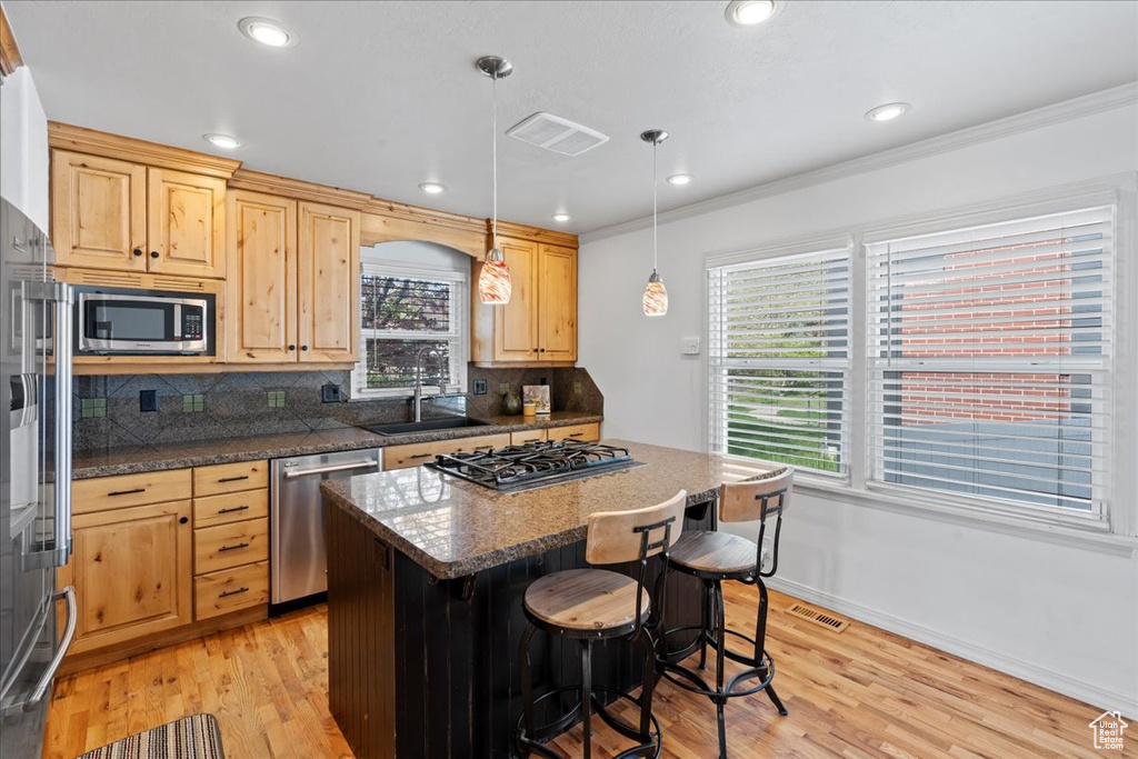 Kitchen featuring light hardwood / wood-style floors, backsplash, stainless steel appliances, and light brown cabinets