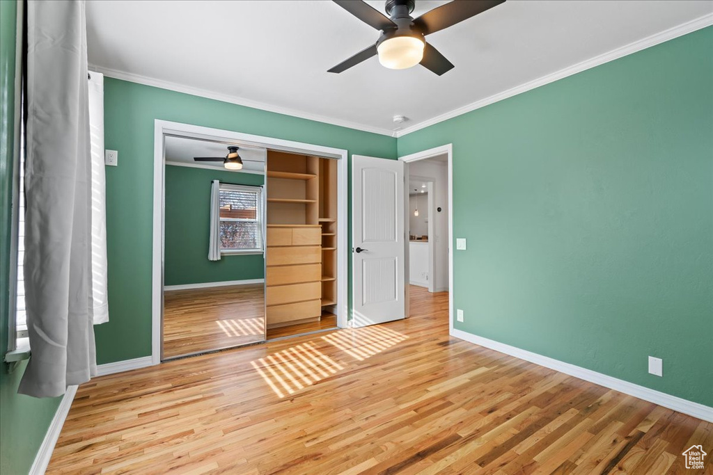 Unfurnished bedroom featuring ornamental molding, a closet, ceiling fan, and light wood-type flooring