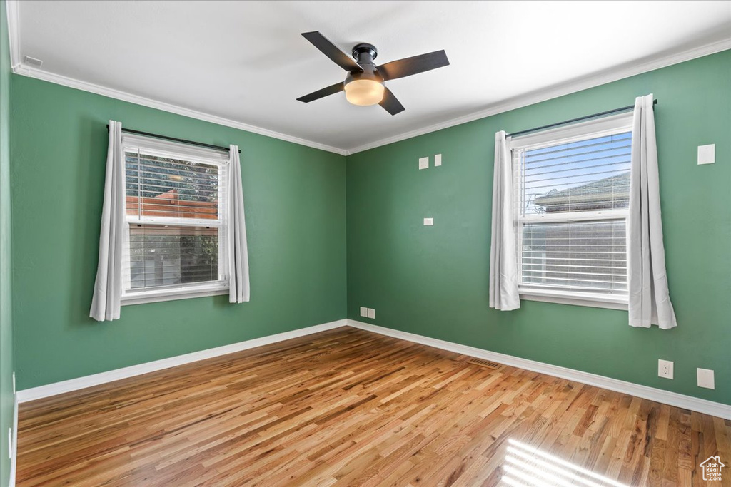 Empty room featuring ornamental molding, ceiling fan, and light wood-type flooring