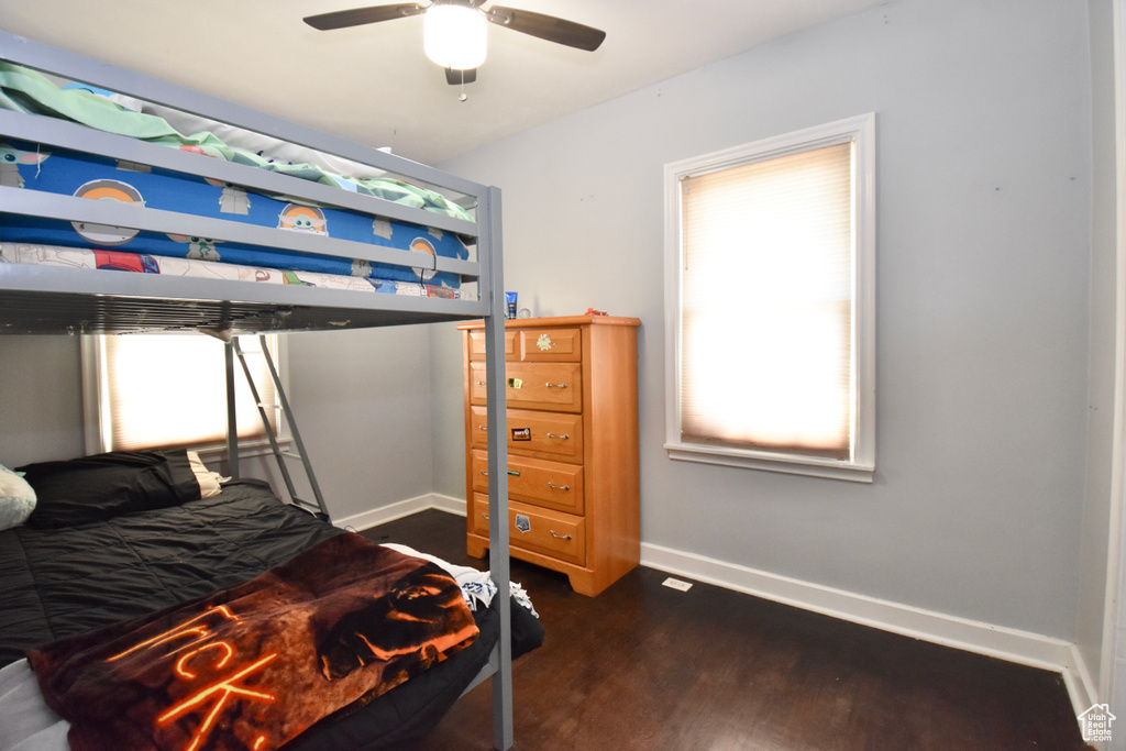 Bedroom with ceiling fan, dark wood-type flooring, and multiple windows