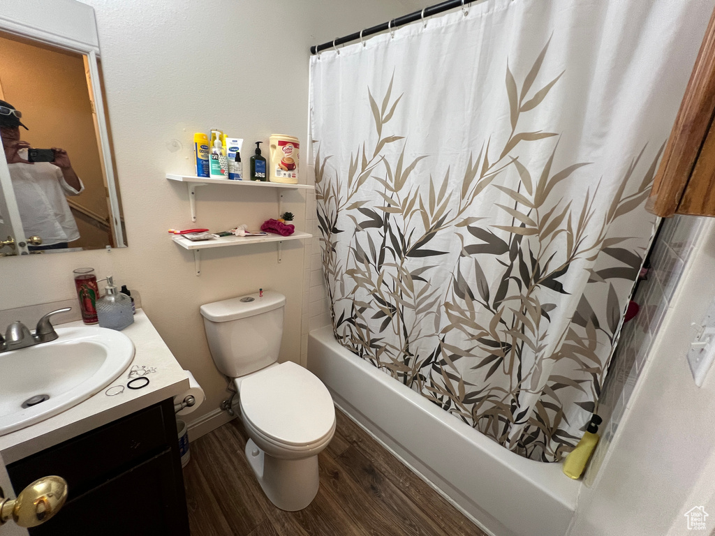 Full bathroom featuring shower / bathtub combination with curtain, wood-type flooring, vanity, and toilet