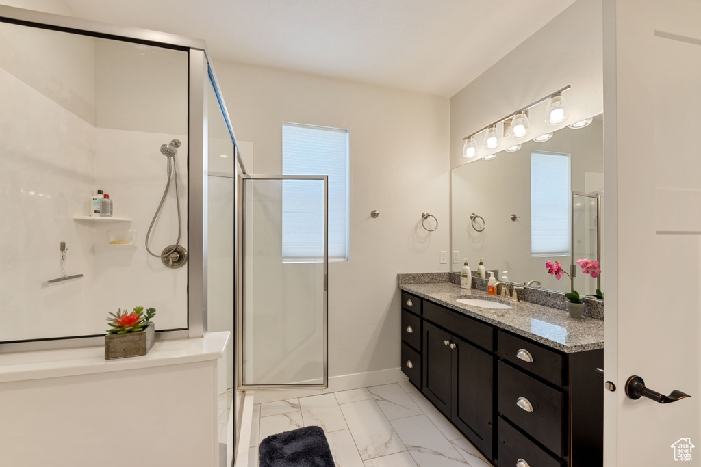 Bathroom featuring a shower with shower door, tile floors, and vanity