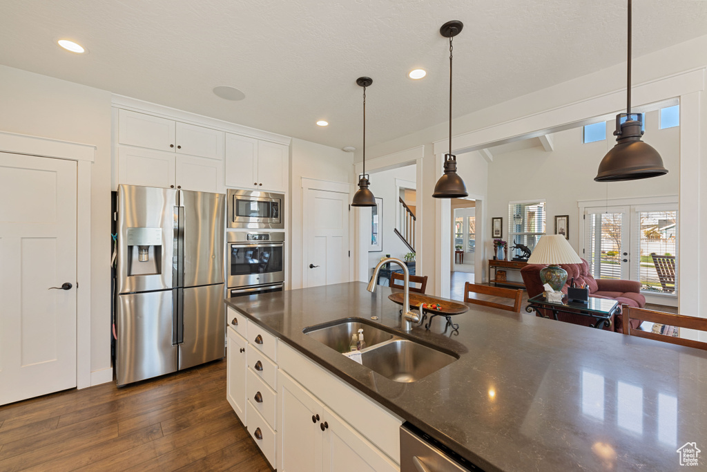 Kitchen featuring decorative light fixtures, sink, appliances with stainless steel finishes, and dark wood-type flooring