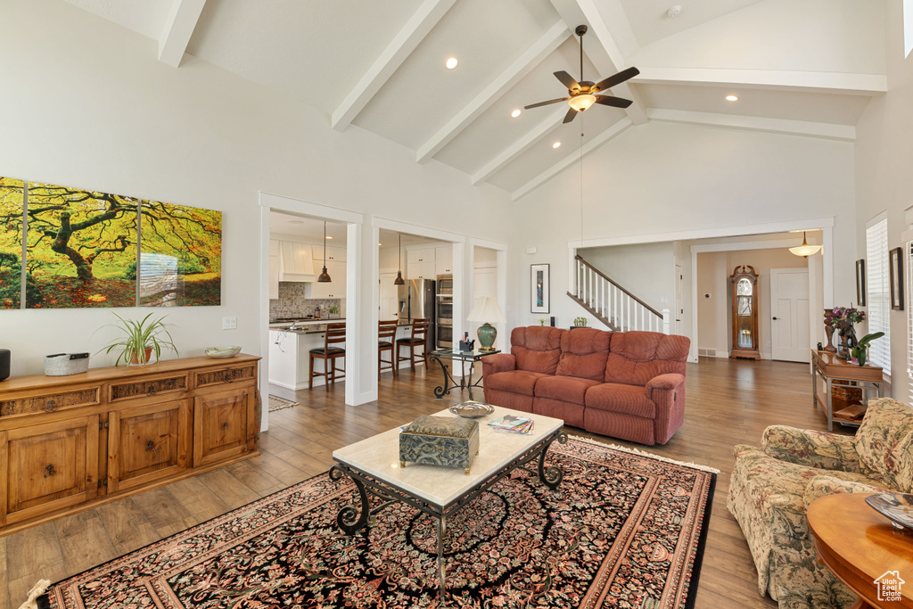 Living room with high vaulted ceiling, beamed ceiling, light hardwood / wood-style flooring, and ceiling fan