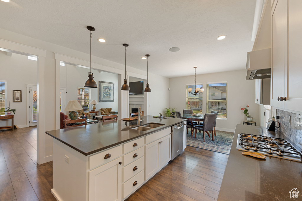 Kitchen featuring sink, pendant lighting, dark hardwood / wood-style flooring, and a center island with sink