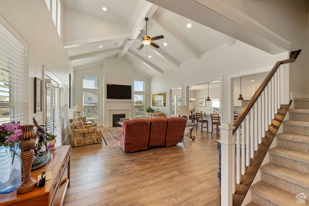 Living room with high vaulted ceiling, light hardwood / wood-style floors, beam ceiling, and ceiling fan