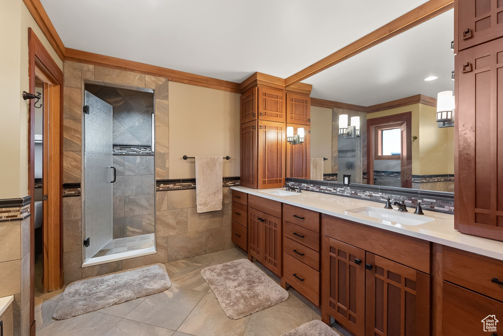Bathroom with an enclosed shower, vanity, crown molding, and tile flooring