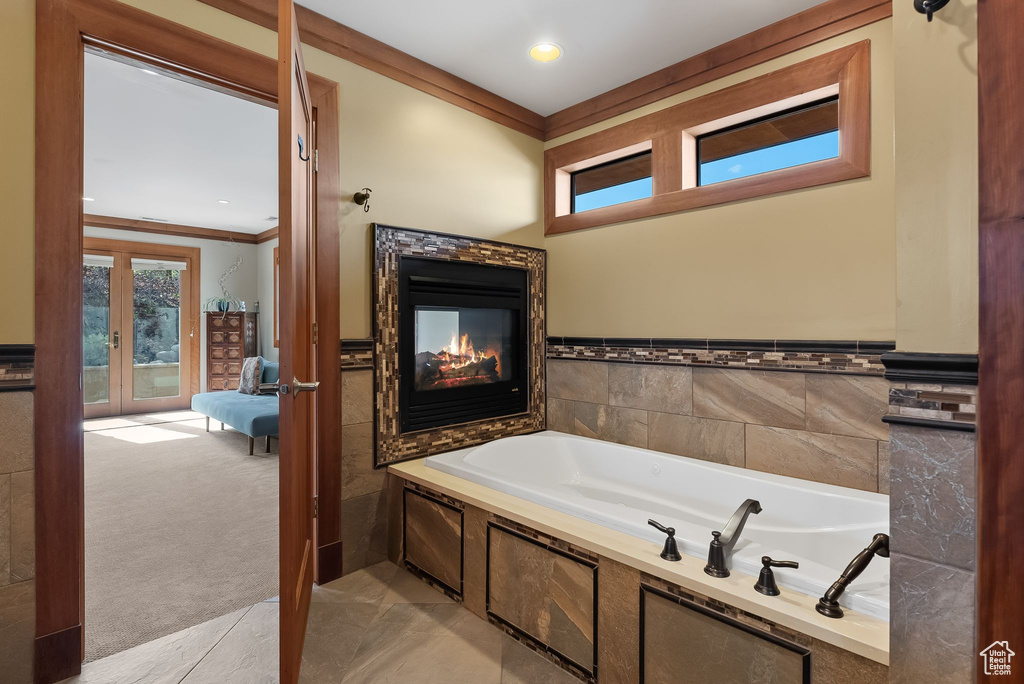 Bathroom featuring french doors, crown molding, a bathing tub, and a multi sided fireplace