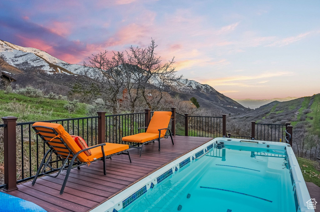 Pool at dusk featuring a deck with mountain view