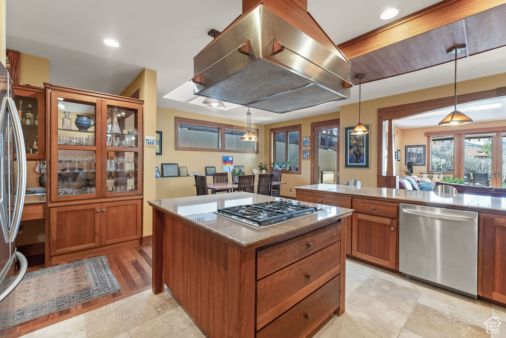 Kitchen with appliances with stainless steel finishes, light tile flooring, pendant lighting, and island range hood