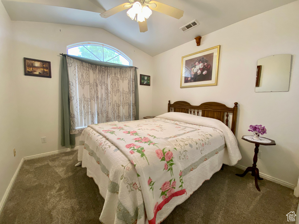 Bedroom with vaulted ceiling, ceiling fan, and dark colored carpet