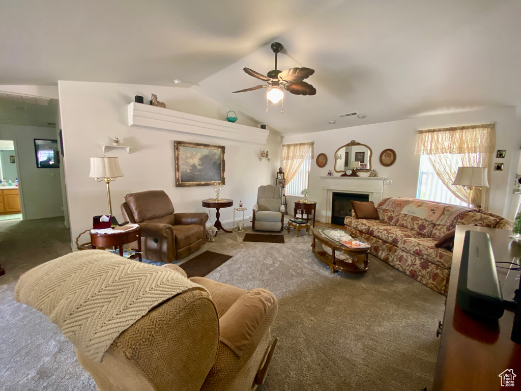 Living room with dark colored carpet, ceiling fan, and lofted ceiling