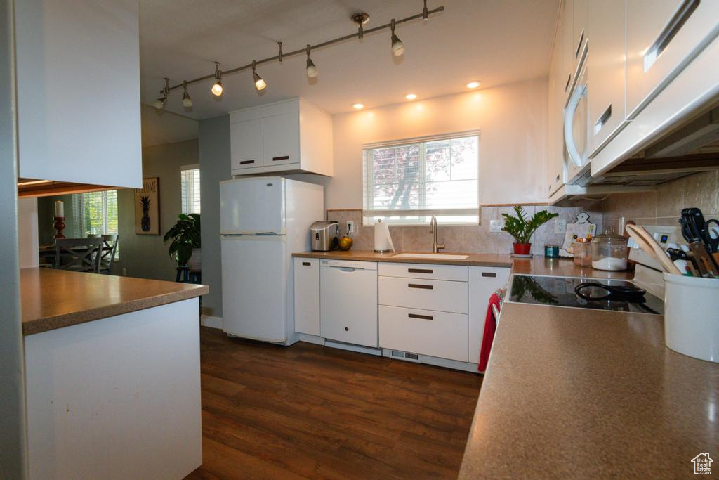 Kitchen with sink, white appliances, tasteful backsplash, white cabinetry, and plenty of natural light
