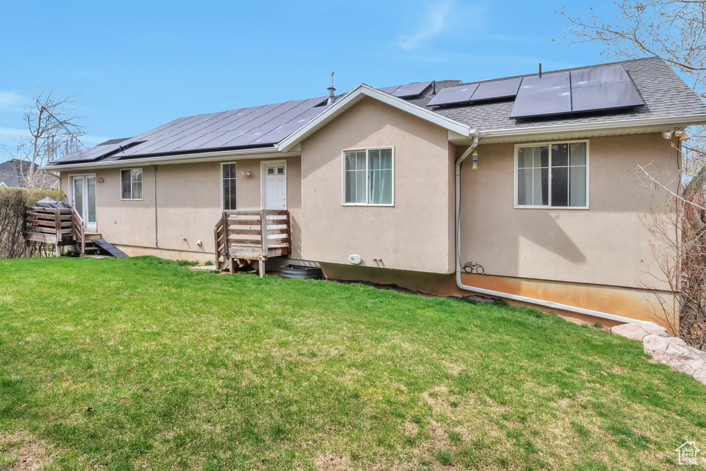 Back of property with solar panels and a lawn