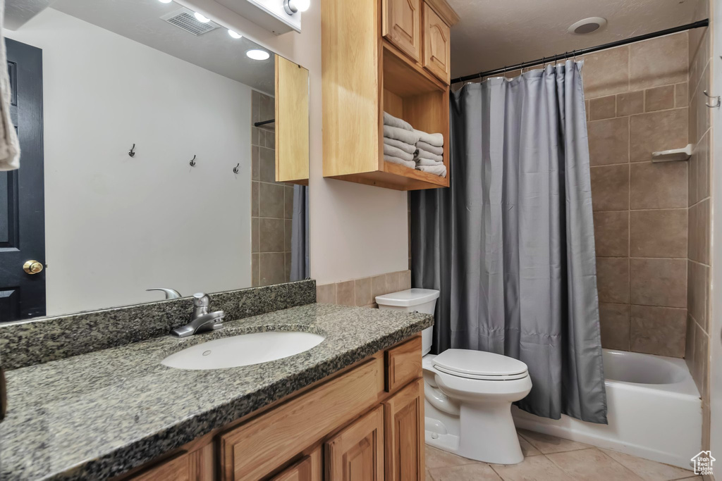 Full bathroom featuring shower / bathtub combination with curtain, toilet, tile floors, and vanity