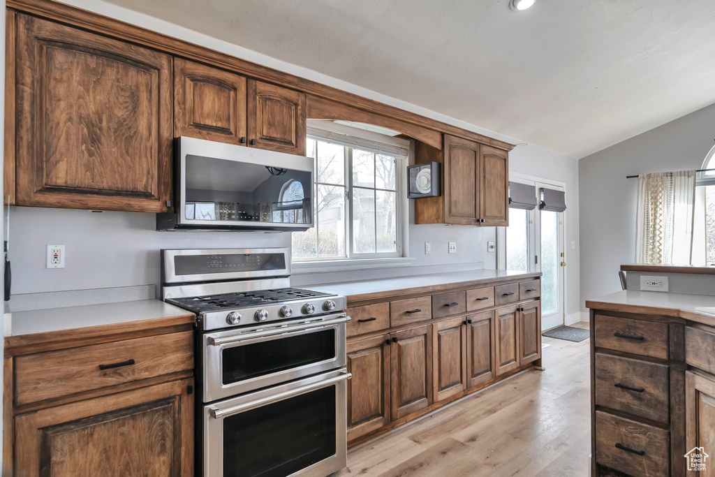 Kitchen with lofted ceiling, stainless steel appliances, and light hardwood / wood-style floors
