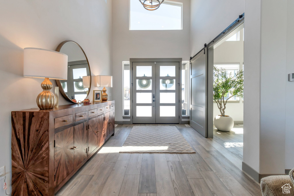 Foyer with french doors, light hardwood / wood-style floors, a towering ceiling, and a barn door
