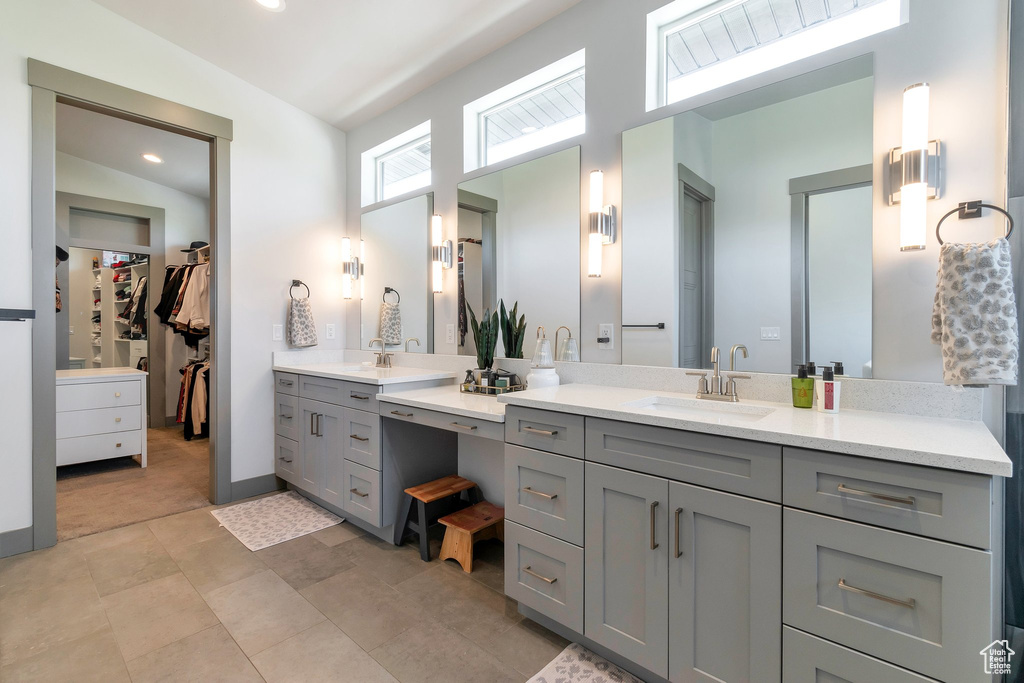 Bathroom featuring large vanity, vaulted ceiling, tile floors, and dual sinks