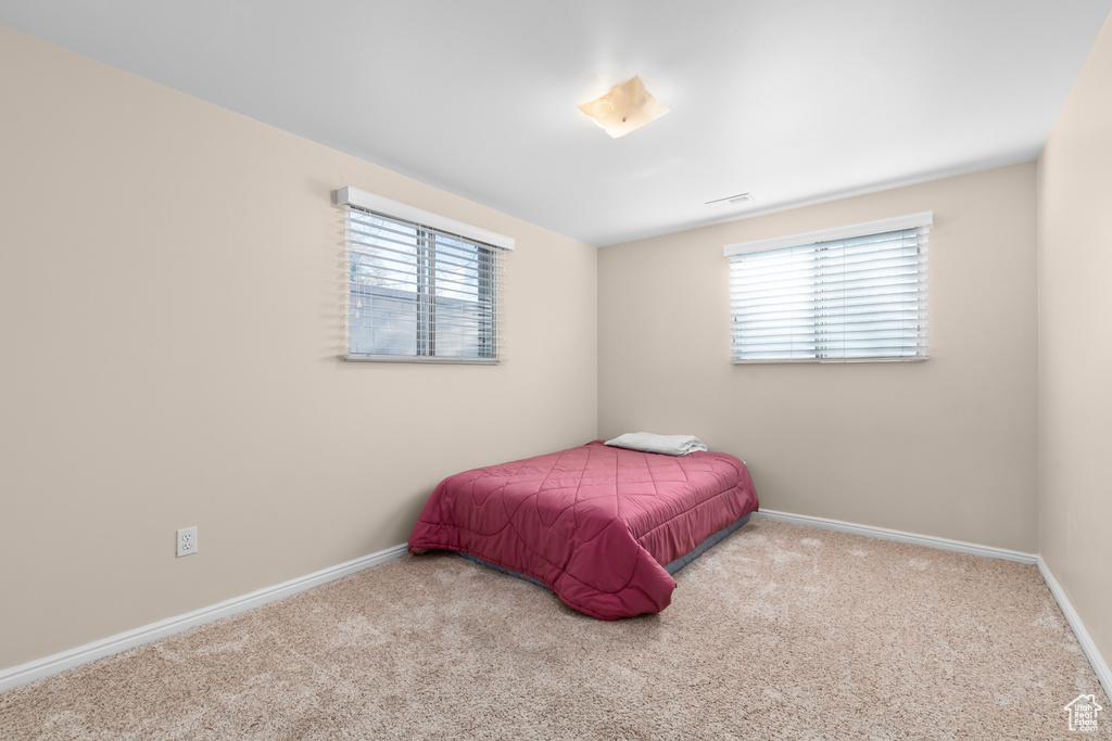 Bedroom featuring light carpet and multiple windows