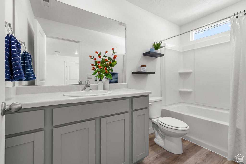 Full bathroom featuring large vanity, shower / bath combo, toilet, and hardwood / wood-style flooring
