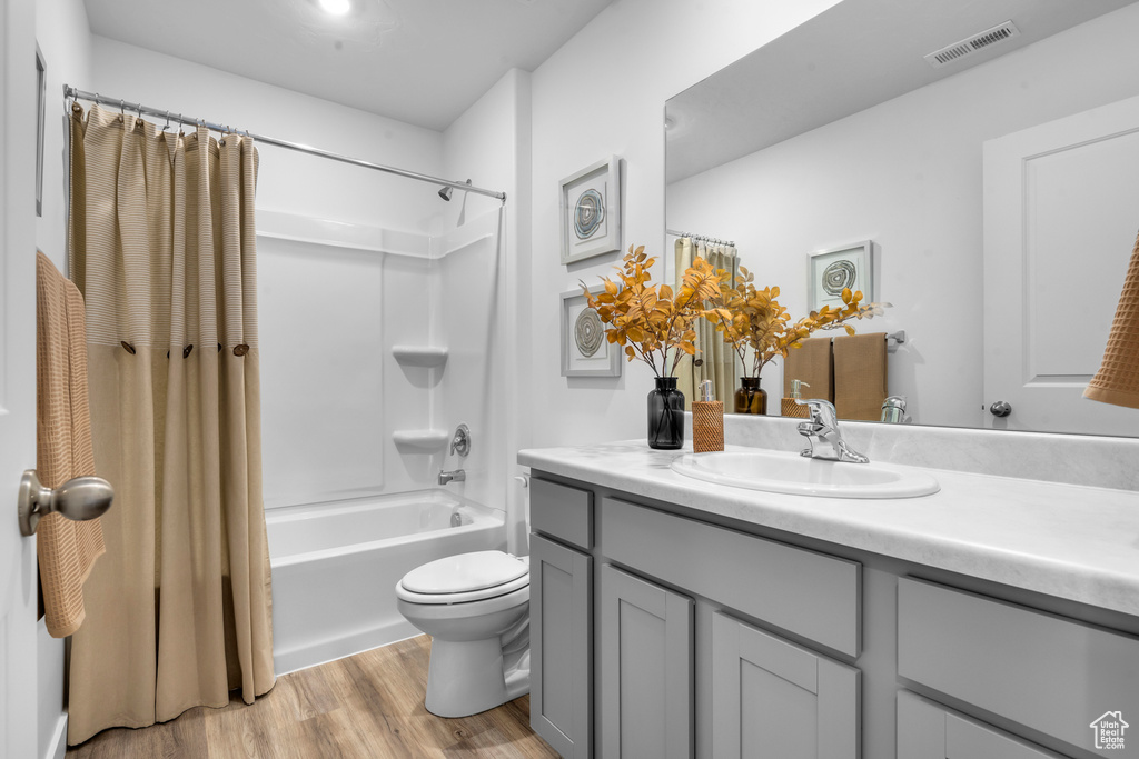 Full bathroom featuring vanity, toilet, hardwood / wood-style flooring, and shower / tub combo