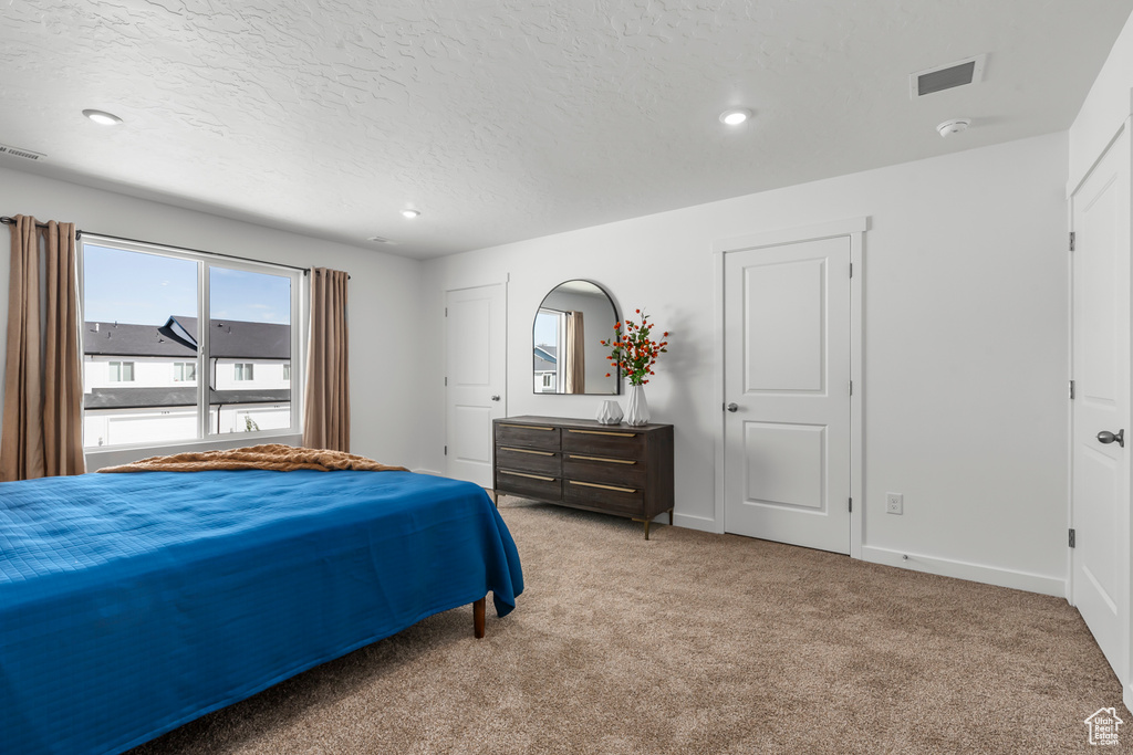 Bedroom featuring a textured ceiling and light carpet