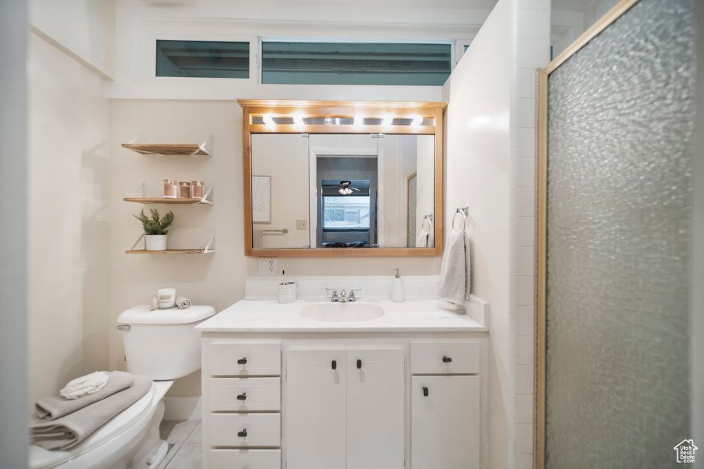 Bathroom with a shower with shower door, toilet, and vanity