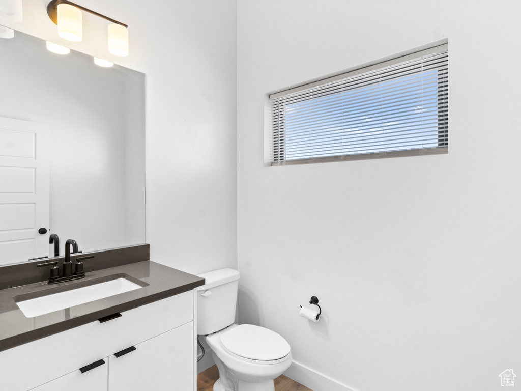 Bathroom featuring vanity with extensive cabinet space, toilet, and hardwood / wood-style flooring