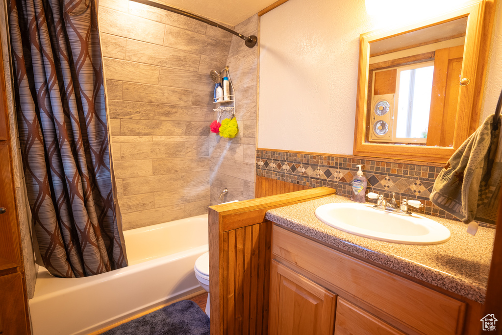 Full bathroom featuring backsplash, shower / bath combination with curtain, toilet, and vanity