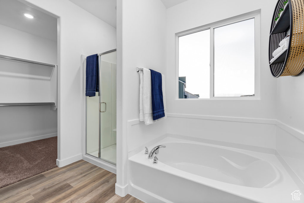 Bathroom with independent shower and bath and hardwood / wood-style flooring