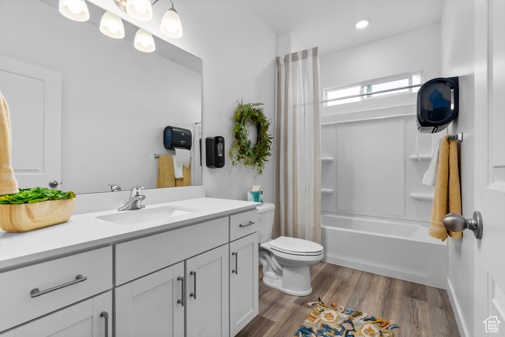 Full bathroom with shower / tub combo with curtain, vanity, toilet, and hardwood / wood-style flooring