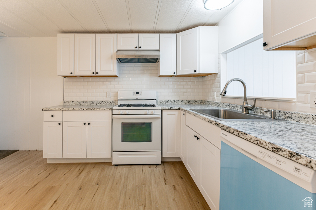 Kitchen featuring stainless steel dishwasher, light wood-type flooring, white cabinetry, and gas range gas stove