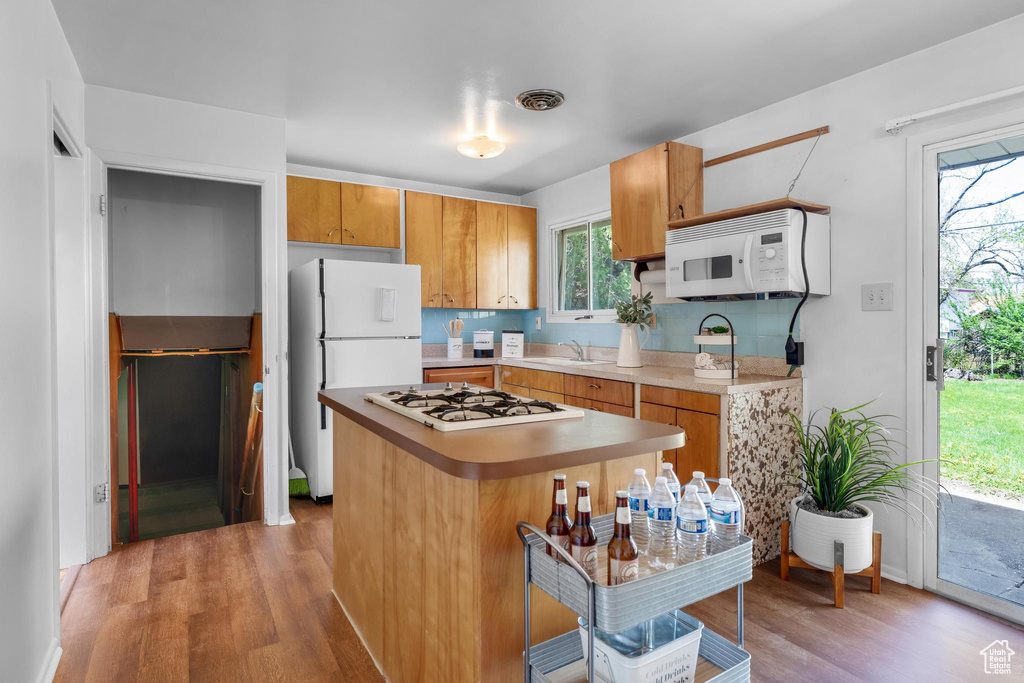Kitchen featuring tasteful backsplash, light hardwood / wood-style floors, white appliances, and sink