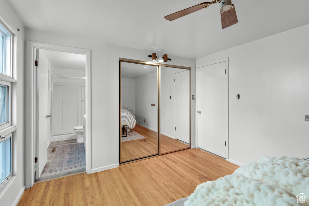 Bedroom featuring ensuite bath, ceiling fan, light wood-type flooring, and a closet