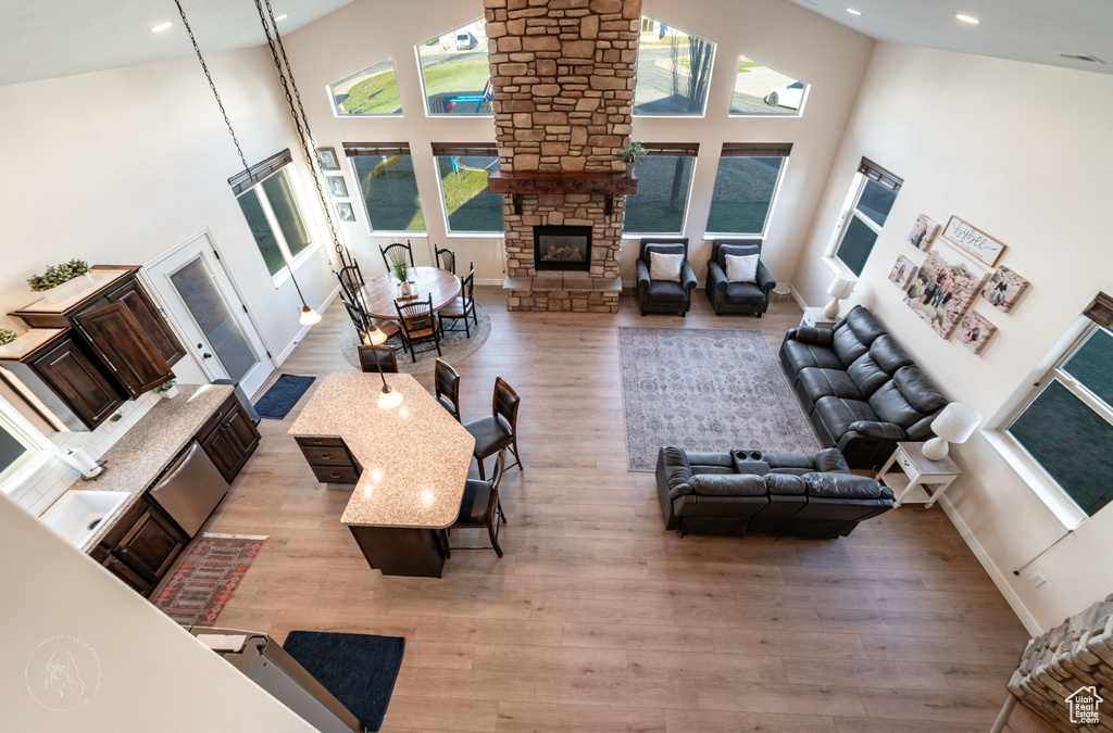 Living room featuring a stone fireplace, light hardwood / wood-style flooring, and high vaulted ceiling