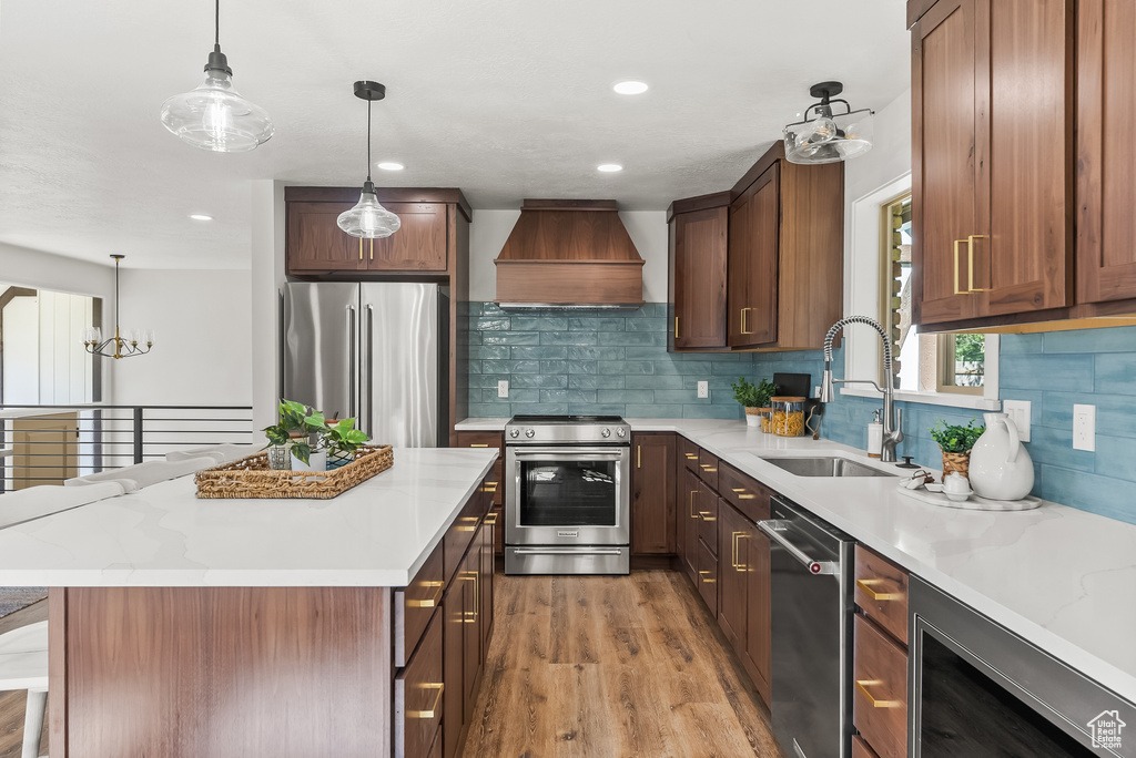 Kitchen featuring light hardwood / wood-style floors, tasteful backsplash, premium range hood, and stainless steel appliances